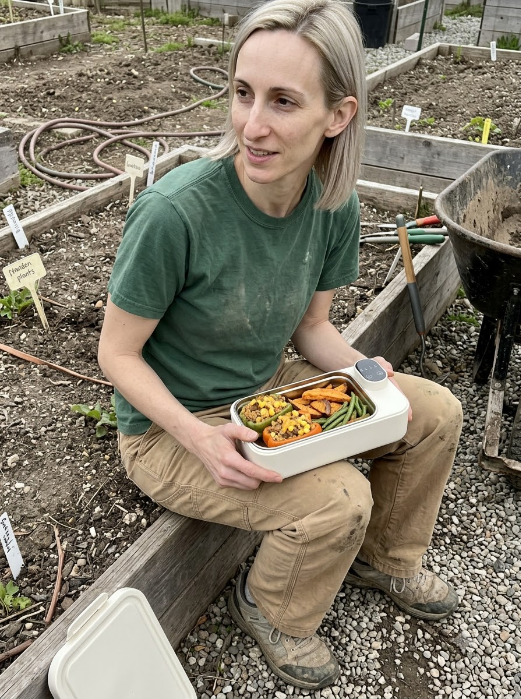 Woman enjoying a warm homemade meal from her THERMAL heated lunch box outdoors.